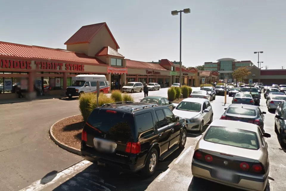 A typical American shopping center, with a thrift store at one end and a parking lot full of cars.
